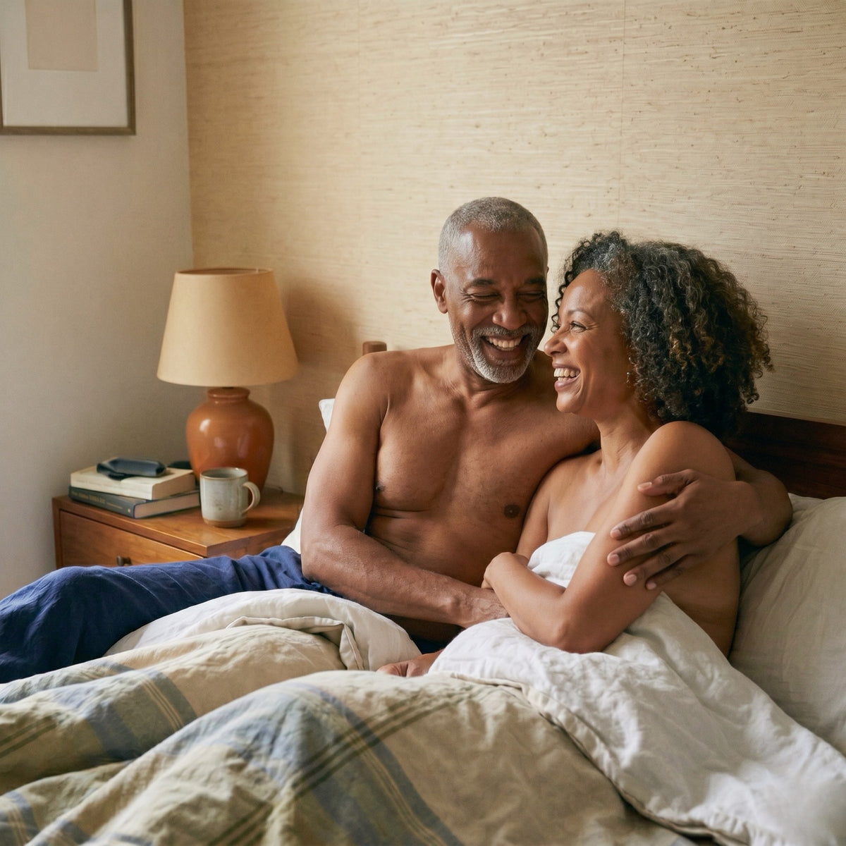 A couple laughing together in bed in the morning