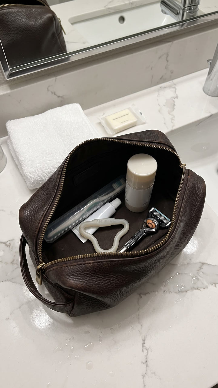 Light Sedgeia ring inside a leather toiletry bag next to a toothbrush and a razor
